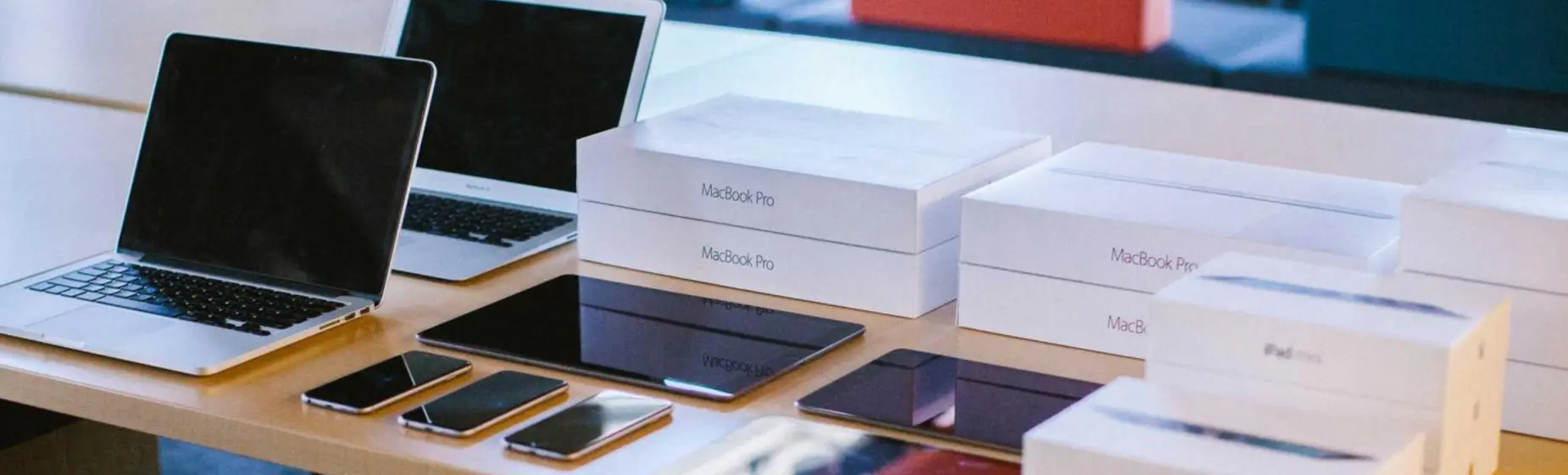 Dispositivos Apple y cajas sobre una mesa, representando despliegue y gestión de movilidad corporativa.